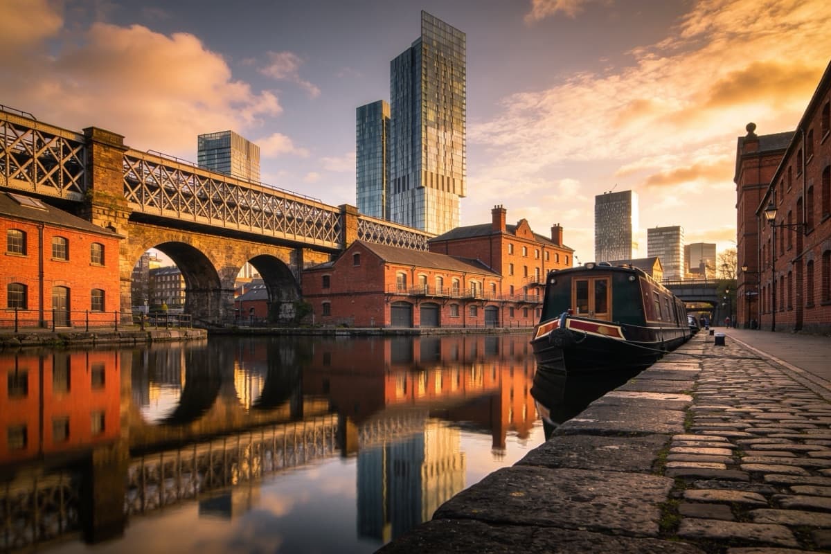 A canal basin with brick warehouses and city towers in Manchester